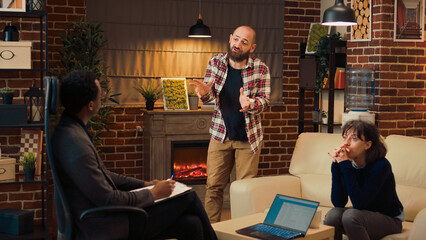 Wall Mural - Displeased husband talking about conflict with specialist at couple therapy session, complaining about relationship problems. Man and woman attending professional counseling meeting.