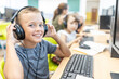© Westend61 - Smiling boy wearing wired headphones in computer class at school