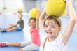 © Westend61 - Smiling girl holding ball on head at school sports court