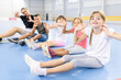 © Westend61 - Students and teacher doing exercise sitting together at school sports court