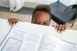 © Westend61 - Playful boy peeking from study table at home