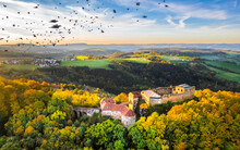 Germany, Baden-Wurttemberg, Drone View Of Flock Of Birds Flying Over Ruined Hohenrechberg Castle At Autumn Dusk