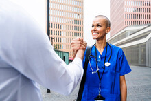 Smiling Mature Nurse Holding Hand Of Doctor On Footpath