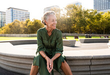 Smiling Mature Woman Sitting On Bench In Park