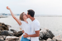 Woman With Hand Raised Kissing Boyfriend At Beach