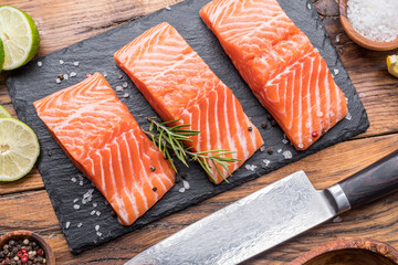 Wall Mural - Fresh salmon fillets on black cutting board with herbs and spices.