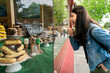 © PR Image Factory - side view of happy asian Japanese woman pointing at yummy cookies in the display window of a bakery with various sweet treats while she's on sidewalk in Carmel by the sea