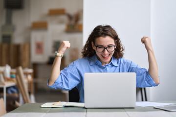 Young happy business woman office worker or student feeling excited winning online looking at laptop celebrating professional achievement, good online exam results, getting hired or approved at work.