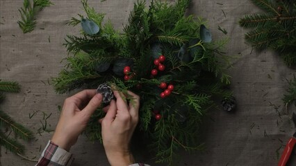 Wall Mural - Hands making evergreen Christmas flower arrangement. DIY Xmas home decoration. 