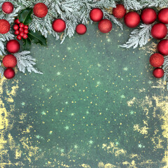 Wall Mural - Christmas retro festive background border with snow covered fir, holly, red tree bauble decorations on grunge green gold. Festive nature Xmas abstract design.
