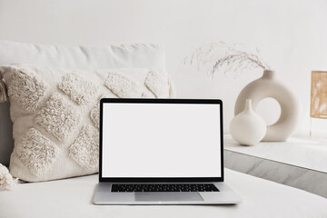 Laptop computer with empty blank mockup screen over white modern living room design. Work place, home office interior. Business, web site advertisement, workspace concept