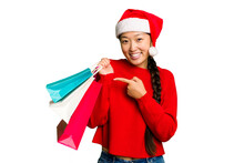 Young Asian Woman Shopping A Christmas Presents Isolated Young Asian Woman Shopping A Christmas Presents Isolated Smiling And Pointing Aside, Showing Something At Blank Space.