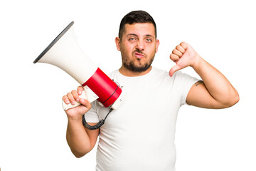 Canvas Print - Young caucasian man holding a megaphone isolated showing a dislike gesture, thumbs down. Disagreement concept.