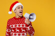 Merry young man in red christmas sweater Santa hat posing hold scream in megaphone announces sale look aside on area workspace isolated on plain yellow background Happy New Year 2023 holiday concept
