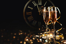 Happy New Year! A Golden Bucket With Champagne, Two Glasses And A Golden Serpentine Against The Background Of A Clock Face.