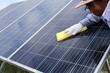 Workers cleaning solar panels. Close-up of a male worker's hand rubbing a solar cell surface to remove dirt in an outdoor power farm with a text copying area and selective focus.