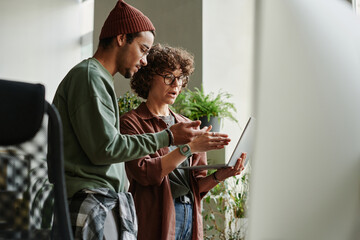 Wall Mural - Two young intercultural programmers discussing online data and expressing view point about video describing software development