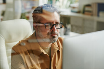 Leinwandbilder - Contemporary aged programmer or IT engineer working in front of computer and looking through information on screen