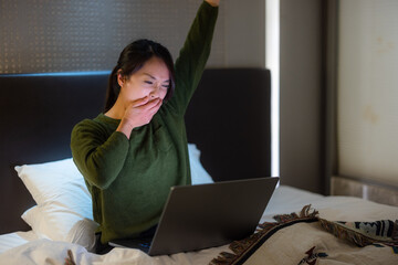 Wall Mural - Woman feel tired on working on computer with sit on bed at night