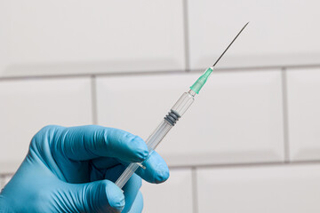 Wall Mural - Close up of doctor's hand in medical gloves with a syringe with Covid-19 serum / vaccine  in front of a laboratory room