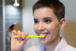 © Solid photos - Young woman washing teeth in the bathroom in front of the mirror in morning