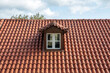 Red tiled roof with attic. Dormer window white color on garret, rooftop.