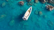 Aerial drone top down photo of white inflatable rib speed boat anchored in tropical exotic rocky bay with emerald sea