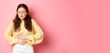 © Mix and Match Studio - Young woman with pain in stomach, holding hands on belly, feeling terrible ache, menstrual cramps, standing against pink background