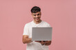 Young handsome smiling man holding laptop and typing on it