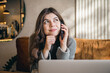 © puhimec - Attractive young woman talking on the phone and working on a laptop.