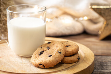 Wall Mural - Christmas cookies and glass of milk for Santa on holiday blurred background.