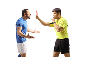 Wall Mural - Profile shot of a football referee blowing a whistle and showing a red card to a confused player