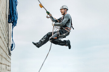 Male worker rope access industrial working at height tank oil wearing harness, helmet safety equipment rope