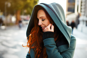 portrait of a stunning red haired woman with beautiful freckles wearing a green coat with big cosy hood. happy pleased facial expression. natural skin with minimum make up