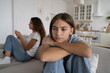 Teenagers-parents misunderstanding. Offended teen girl sitting back to mother feeling sad after fight with mum, teenage daughter thinking of conflict with mom. Parent spending too much time on phone