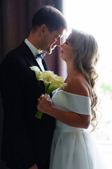 Wall Mural - gentle and in love blonde bride and groom by the window. 