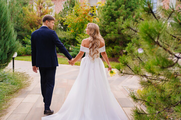 Wall Mural - newlyweds. groom and bride in traditional wedding clothes walk in park