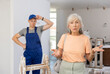 © JackF - Senior woman making helpless gesture because of failure made by young man builder assistant who working in construction site for first time.