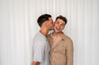 © Andy Connell - Beautiful Gay couple kissing on cheek and smiling  with white curtain background