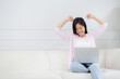 Happiness young asian woman sitting on sofa and working on laptop computer while successful and excitement at home, freelance female using notebook and achievement, business and lifestyles concept.