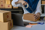 Fototapeta Tulipany - SME business, online sales at home, Asian woman working with boxes and laptops to take orders from customers, parcel delivery concept, online business SME