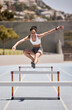 Fitness, training and woman jumping hurdles for sports, exercise and intense cardio on a running track. Black woman, running and hurdling workout for speed, energy and physical performance at stadium
