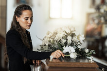 Funeral, Sad And Woman With Flower On Coffin After Loss Of A Loved One, Family Or Friend. Grief, Death And Young Female Putting A Rose On Casket In Church With Sadness, Depression And Mourning