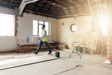 Construction, house and contractor walking in a building with maintenance, renovation and work with sunshine. Architecture, home renovation and fast construction worker on a site working as a builder