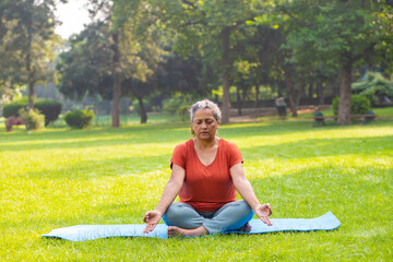 Wall Mural - indian woman doing breathing yoga exercise in the park, Asian female meditation pose, healthcare.