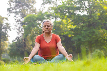 Wall Mural - indian woman doing breathing yoga exercise in the park, Asian female meditation pose, healthcare.