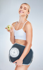 Wall Mural - Health, lose weight and woman with an apple and scale for body goal, motivation and nutrition against a grey studio background. Food, happy and portrait of athlete model with smile for fruit and diet