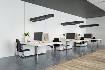 Wall Mural - Perspective view on stylish coworking office work places with modern computers on light tables, black lamps and chairs on dark concrete and wooden floor. 3D rendering