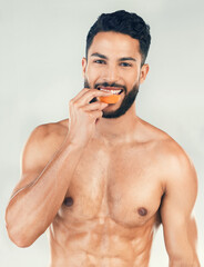 Poster - Portrait, fitness and man eating an orange in studio for vitamin c, healthy skin and self care after training. Nutrition, wellness and happy fitness model on a diet enjoys raw fruit after a workout