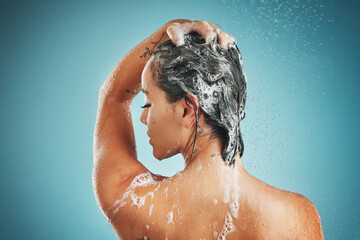 Canvas Print - Beauty, shower and woman cleaning, haircare and shampoo while washing against a blue studio mock up background. Back, model and clean in bathroom for skincare, health and wellness with water and soap